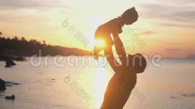 快乐的父亲和女儿在海滩上玩惊人的日落与镜头耀斑效果。 爸爸手里拿着可爱的女孩